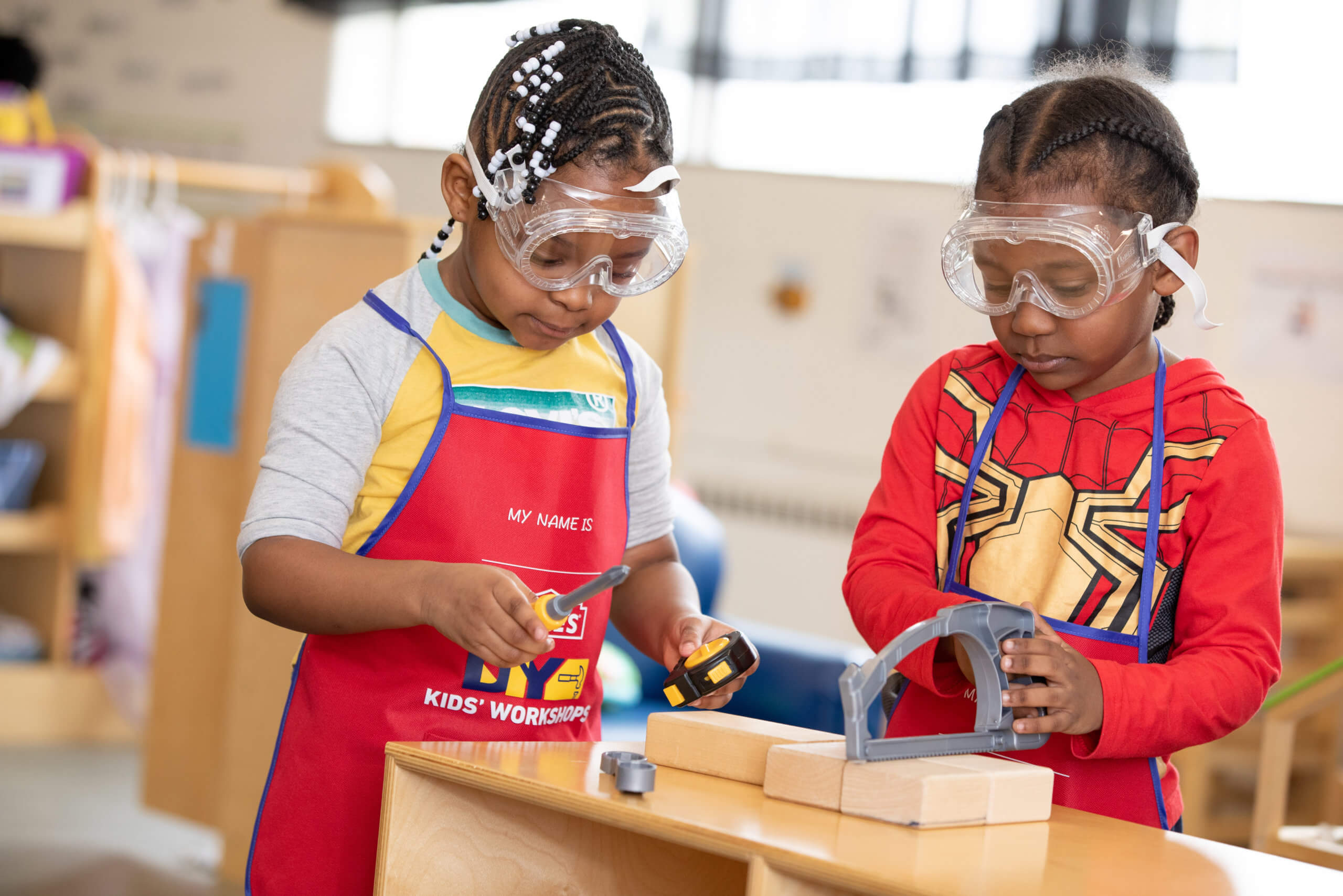 Two young students work at wood shop with plastic tools and their Lowe's DIY workshop