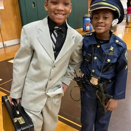 Two young kids dressed in a suit and as a police officer for career day